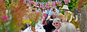 People on a long table at a street party with Union Jack bunting