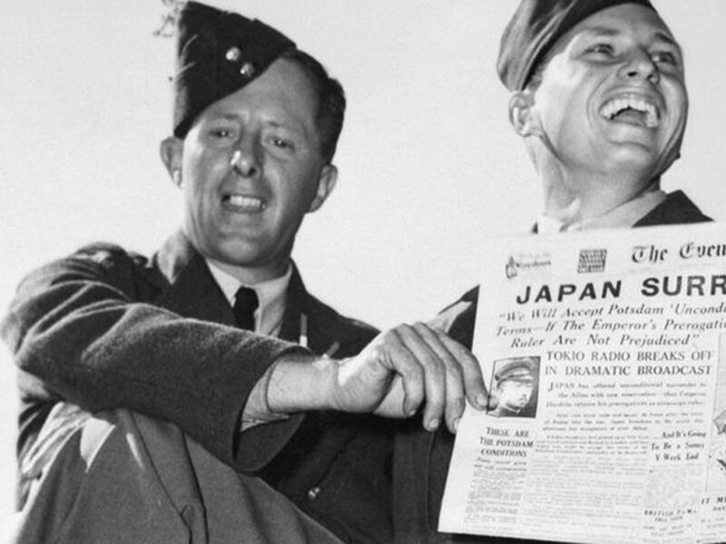 Japan Surrenders headline on newspaper held up by two soliders